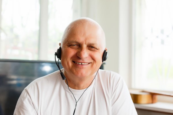 A man with a VOIP headset on, smiling a lot